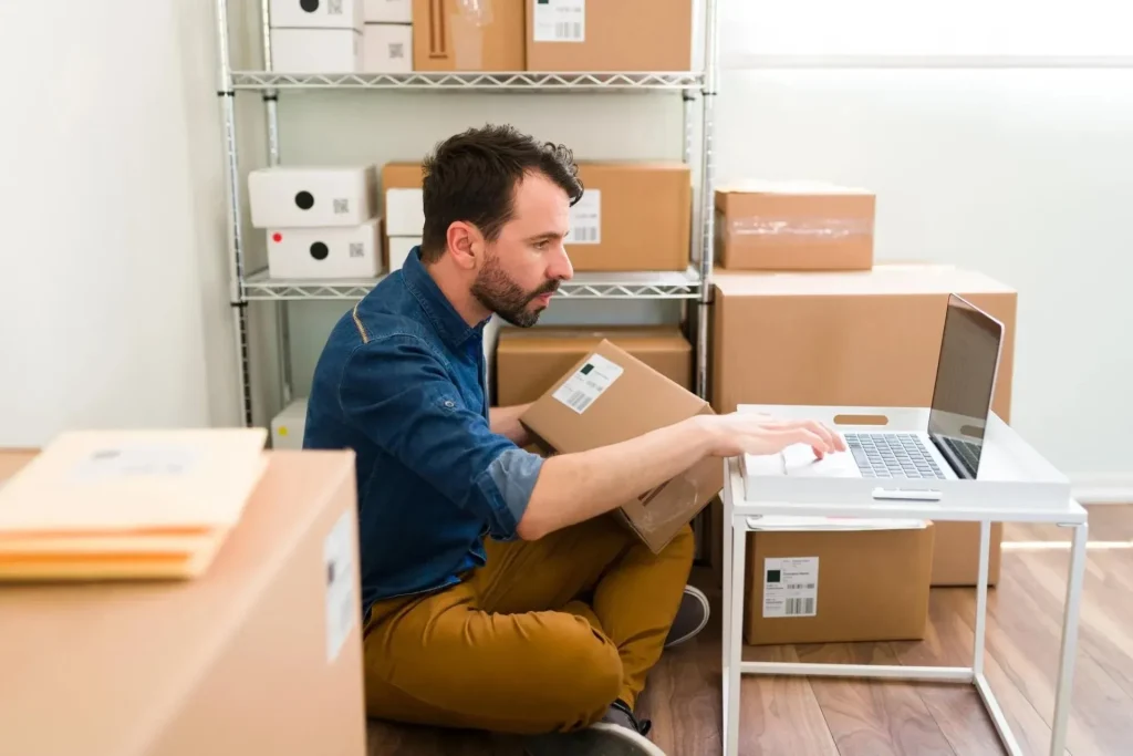 Cómo desarrollar un eCommerce exitoso 1 blog uhura como desarrollar hombre hispano sentado en el piso de su oficina mientras escribe en su laptop y chequea ordenes de cliente de ecommerce