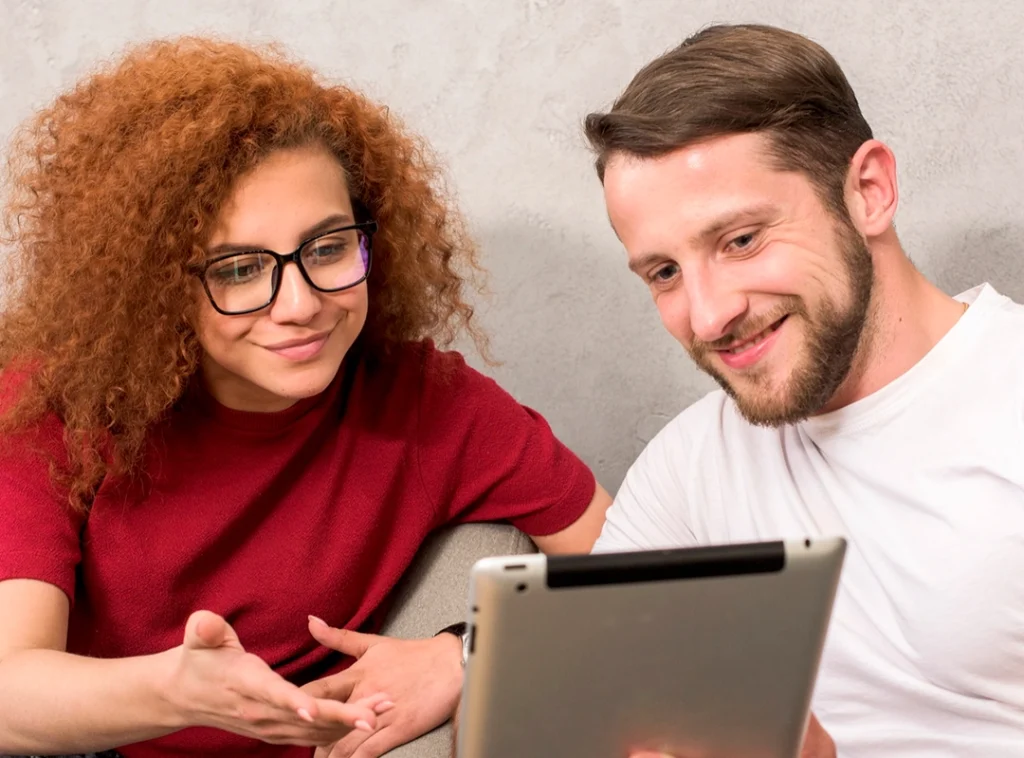 hombre y mujer jovenes revisando tablet (página soluciones digitales Uhura)