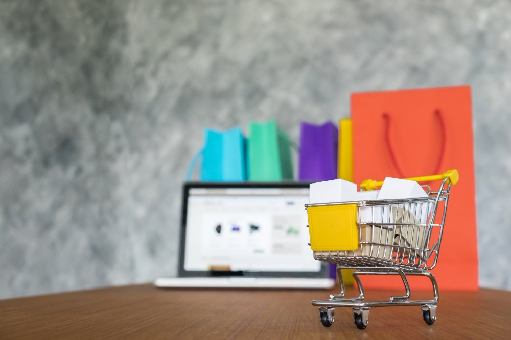 imagen carro de compras en miniatura, portatil y bolsas de compra