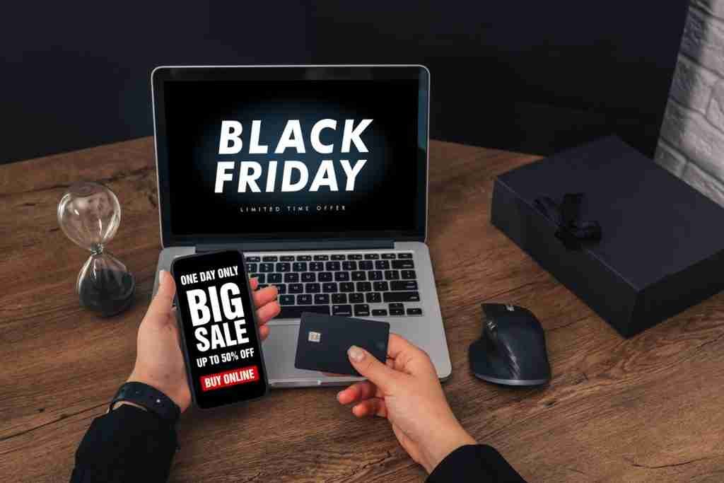 mujer sosteniendo-tarjeta de credito escribiendo teclado portatil venta black friday en pantalla